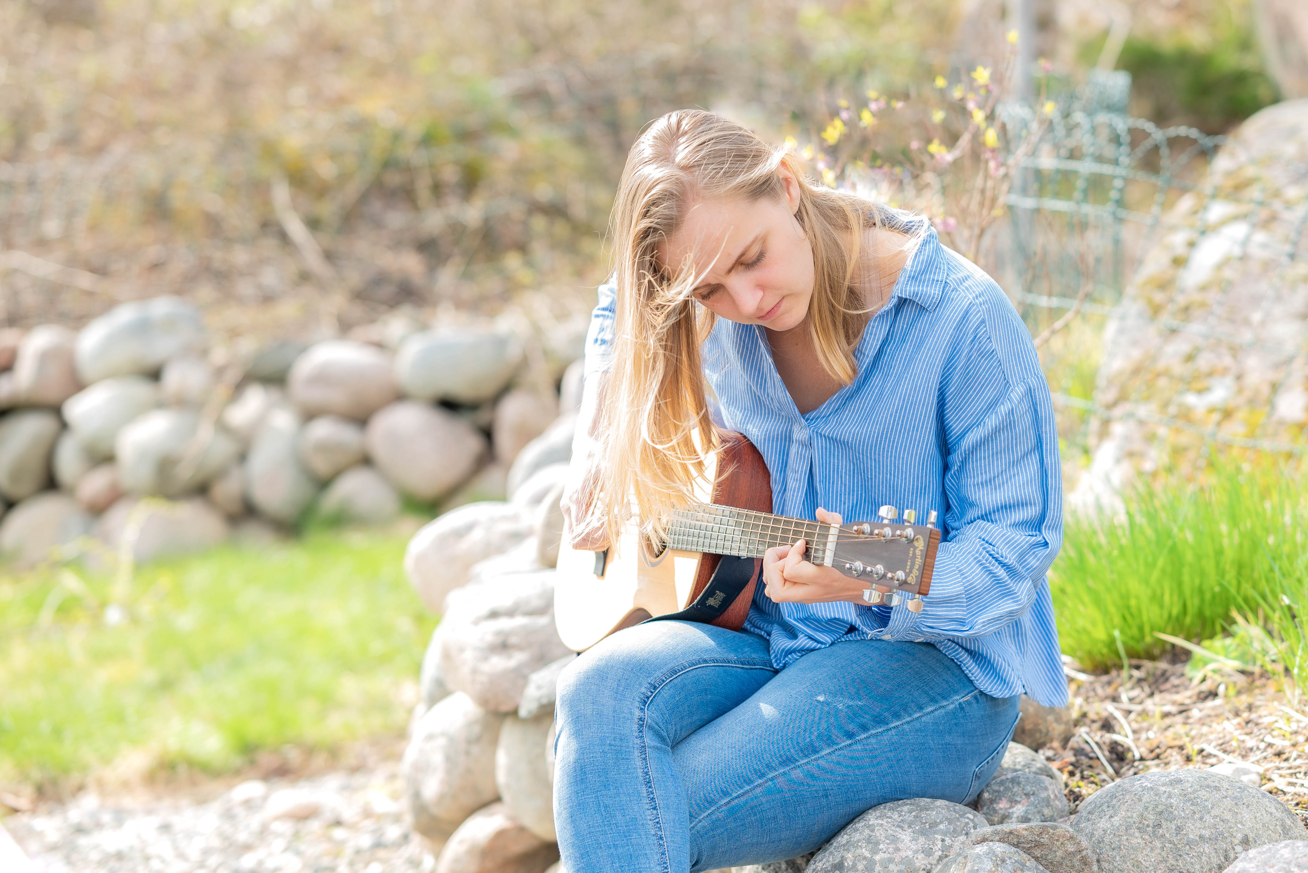 Elin Evelina sjunger och spelar akustisk gitarr i dagsljus